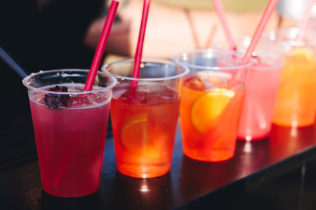 Barman mixing liquor beverages and alcohol drinks in plastic cups, bartender working, beautiful row...