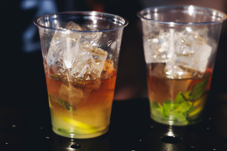 Barman mixing liquor beverages and alcohol drinks in plastic cups, bartender working, beautiful row...