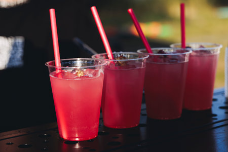 Barman mixing liquor beverages and alcohol drinks in plastic cups, bartender working, beautiful row...