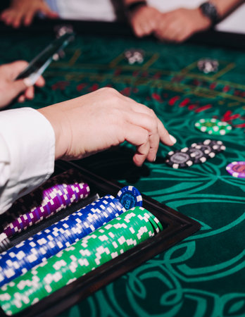 Casino table with roulette wheel in motion, with casino chips, tokens, the hand of croupier, and a...