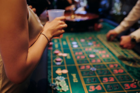 Casino table with roulette wheel in motion, with casino chips, tokens, the hand of croupier, dollar...