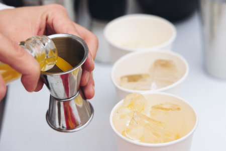 Barman mixing liquor beverages and alcohol drinks in plastic cups, bartender working, beautiful row...