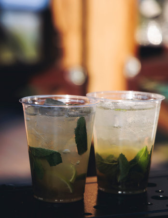 Barman mixing liquor beverages and alcohol drinks in plastic cups, bartender working, beautiful row...