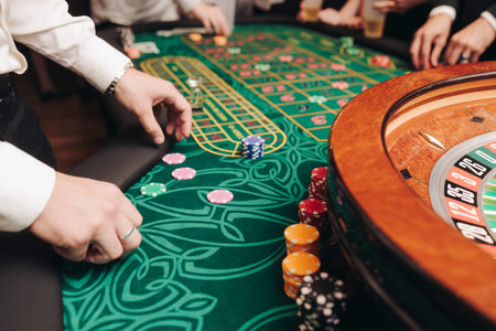 Casino table with roulette wheel in motion, with casino chips, tokens, the hand of croupier, dollar...