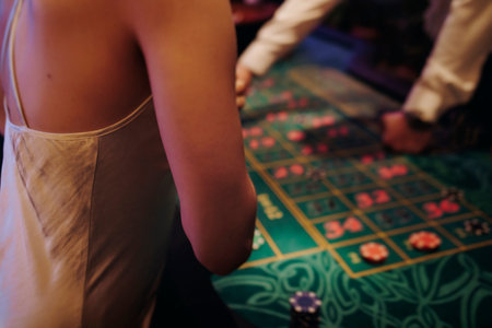 Casino table with roulette wheel in motion, with casino chips, tokens, the hand of croupier, dollar...
