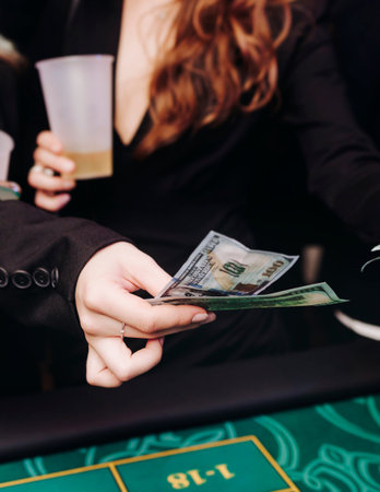 Casino table with roulette wheel in motion, with casino chips, tokens, the hand of croupier, dollar...