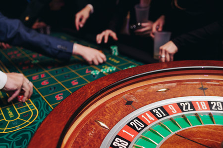 Casino table with roulette wheel in motion, with casino chips, tokens, the hand of croupier, dollar...
