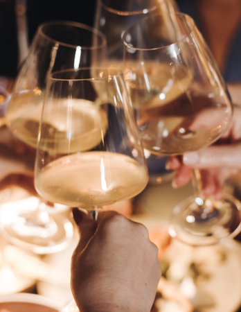 Group of guests celebrate and raise glasses, toasting and cheering with alcohol glasses with wine...