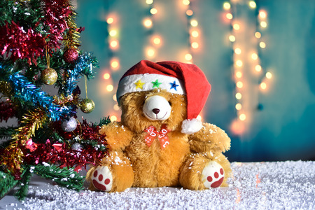 Teddy Bear wear hat in Christmas and Multi colored balls on christmas tree with Blur light Background.の写真素材