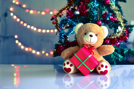 Teddy Bear wear hat in Christmas and Multi colored balls on christmas tree with Blur light Background.の写真素材