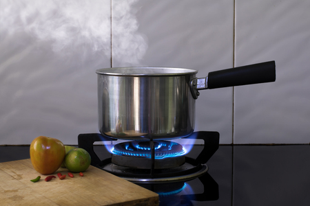 Hot steam on Metal pot on the flame gas stove for boiling water Soup.の写真素材