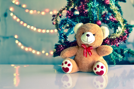 Teddy Bear wear hat in Christmas and Multi colored balls on christmas tree with Blur light Background.の写真素材
