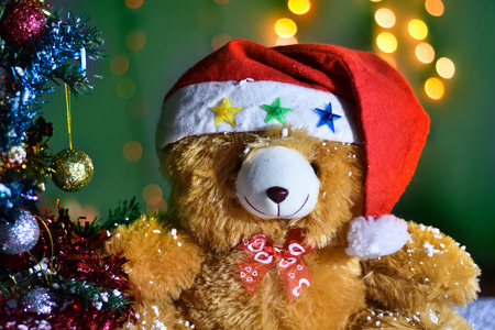 Teddy Bear wear hat in Christmas and Multi colored balls on christmas tree with Blur light Background.の写真素材
