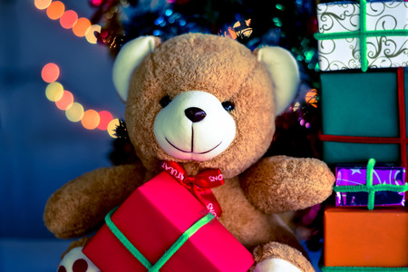 Teddy Bear in Christmas day and Gift Box with christmas tree with Blur light Background.の写真素材