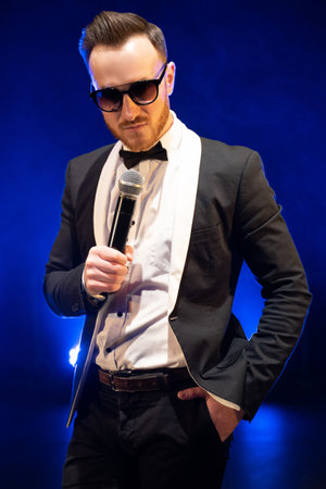 handsome presenter and showman in a stylish suit with a microphone on stage