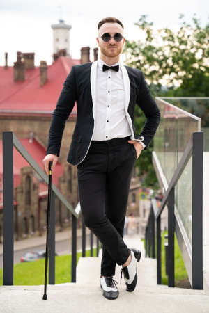 handsome fashionable guy dressed in retro style with glasses and cane