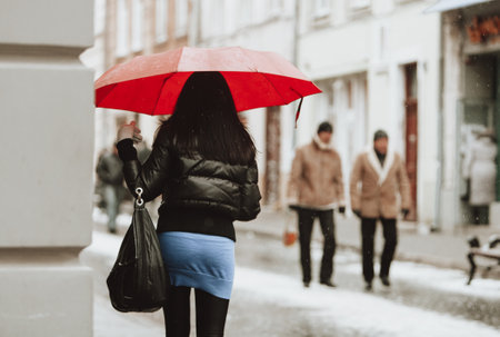 a beautiful girl with an umbrella walks down the street in winterの写真素材