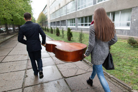 two people are carrying a large cello in the streetの写真素材