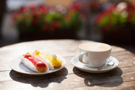 a mug of coffee on a table and a delicious eclair on a plate