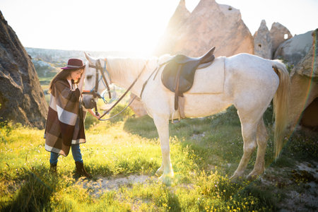 beautiful girl outdoors in the mountains with her faithful horseの写真素材