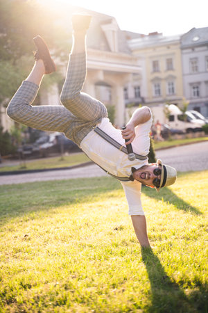 handsome presenter and showman in a stylish suit and hat with a microphone poses with the best emotions and acrobatic tricksの写真素材