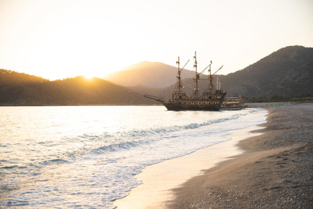 a large ship is docked at the seashore at sunset and beautiful mountainsの写真素材