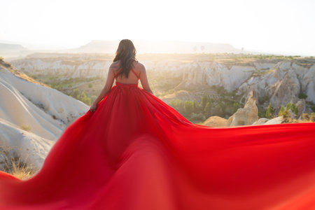 a girl in a flying dress with a long train on the background of balloons in Cappadociaの写真素材