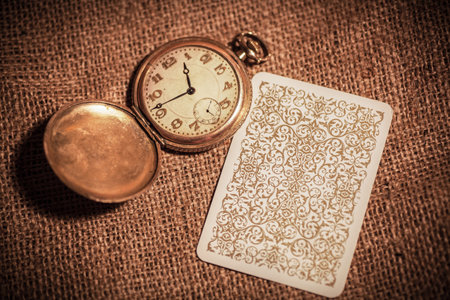 a still life of four playing cards on burlap and a beautiful still life with old books and a clockの写真素材