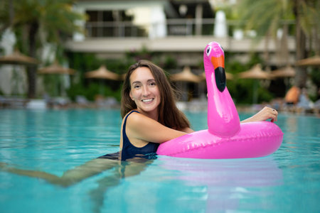 beautiful girl in a swimsuit in a swimming pool with an inflatable pink flamingo