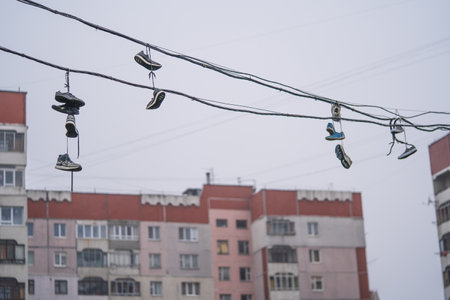 many pairs of shoes hang high on the wires between the housesの写真素材