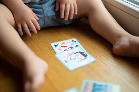 a small child plays with developing cards from a board gameの写真素材