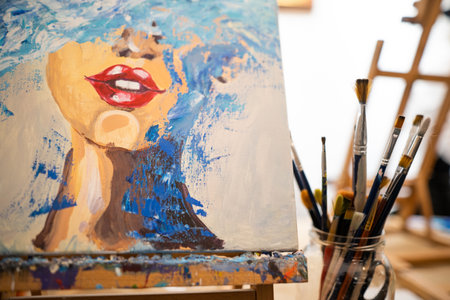 close-up of many brushes and a painted picture in an art studioの写真素材