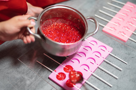 process of making delicious lollipops by pouring them into moldsの写真素材