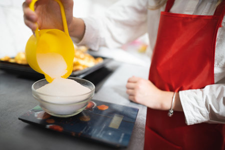 the cook pours sugar into a bowl on the scalesの写真素材