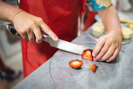 pastry chef cuts strawberries with a knife for baking sweet dessertsの写真素材