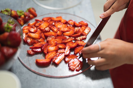 pastry chef cuts strawberries with a knife for baking sweet dessertsの写真素材
