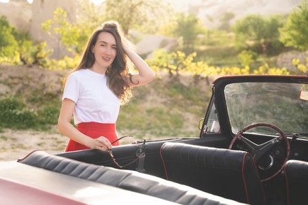 beautiful happy girl in a skirt posing near a retro car in the mountains of cappadocia