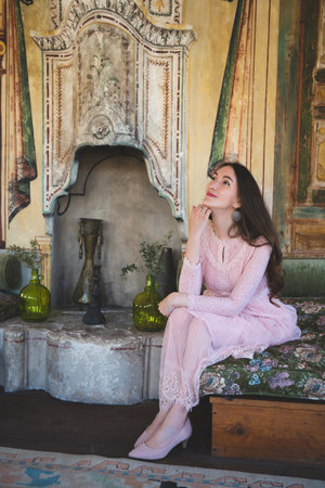 a beautiful girl in a pink dress poses in a room with a traditional Turkish interior