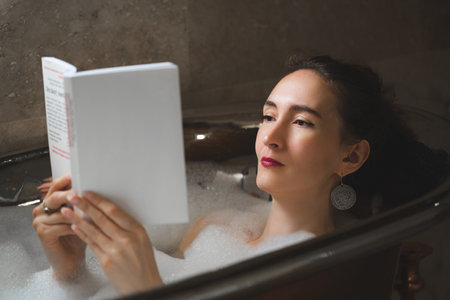 beautiful sexy girl in a bubble bath reading a book