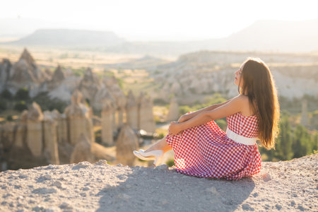 a beautiful girl in a retro dress at sunrise is happy posing against the background of the mountain landscape in Cappadociaの写真素材