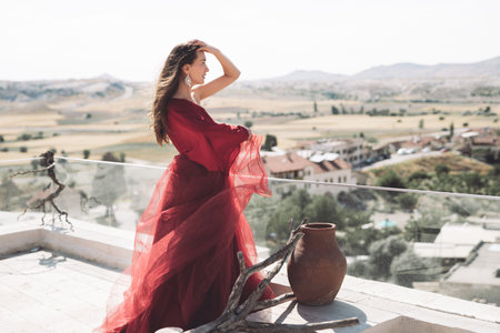 A girl in a flying dress on the roof of a house on ancient city backgroundの写真素材