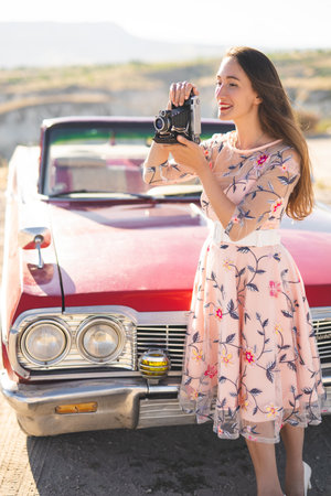 beautiful girl in a retro dress takes pictures on camera on mountain landscape in Cappadocia near a...