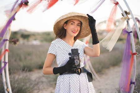 beautiful girl in retro dress and old camera posing on lavender field with sceneryの写真素材