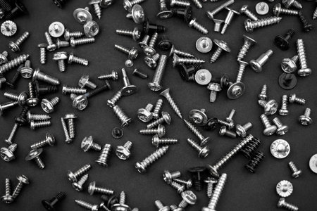 many different screws scattered on a black background