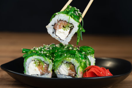 delicious traditional Japanese sushi and rolls on a plate holding chopsticksの写真素材