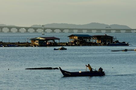 George Town, Penang/Malaysia - Feb 27 2016: A fisherman row the boat with the fish farm at the back.