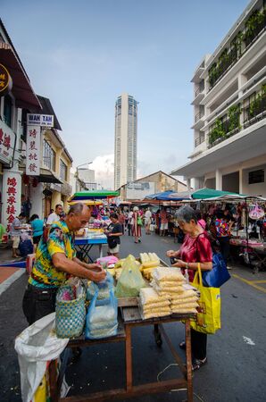 George Town, Penang/Malaysia - Aug 07 2016: Woman but\y food at the morning market. Back is KOMTAR building.のeditorial素材