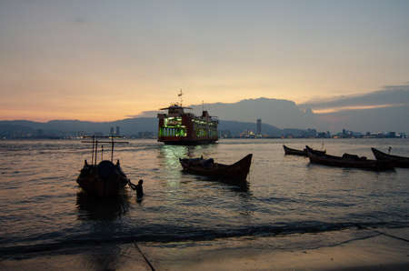 George Town, Penang/Malaysia - Jun 12 2017: Penang ferry and traditional fishing boat in dusk hour.のeditorial素材