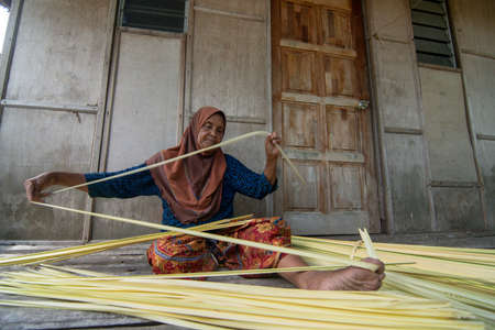 Kelantan/Malaysia - Jul 15 2017: An experience woman make cigarette from dried Nipah leaves.のeditorial素材