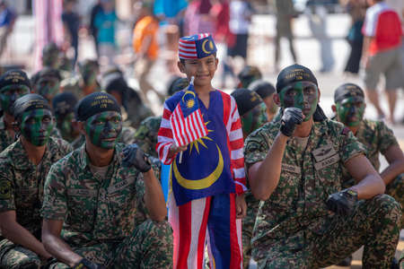 George Town, Penang/Malaysia - Aug 31 2017: A kid wear Malaysia costume take photo with soldier.のeditorial素材